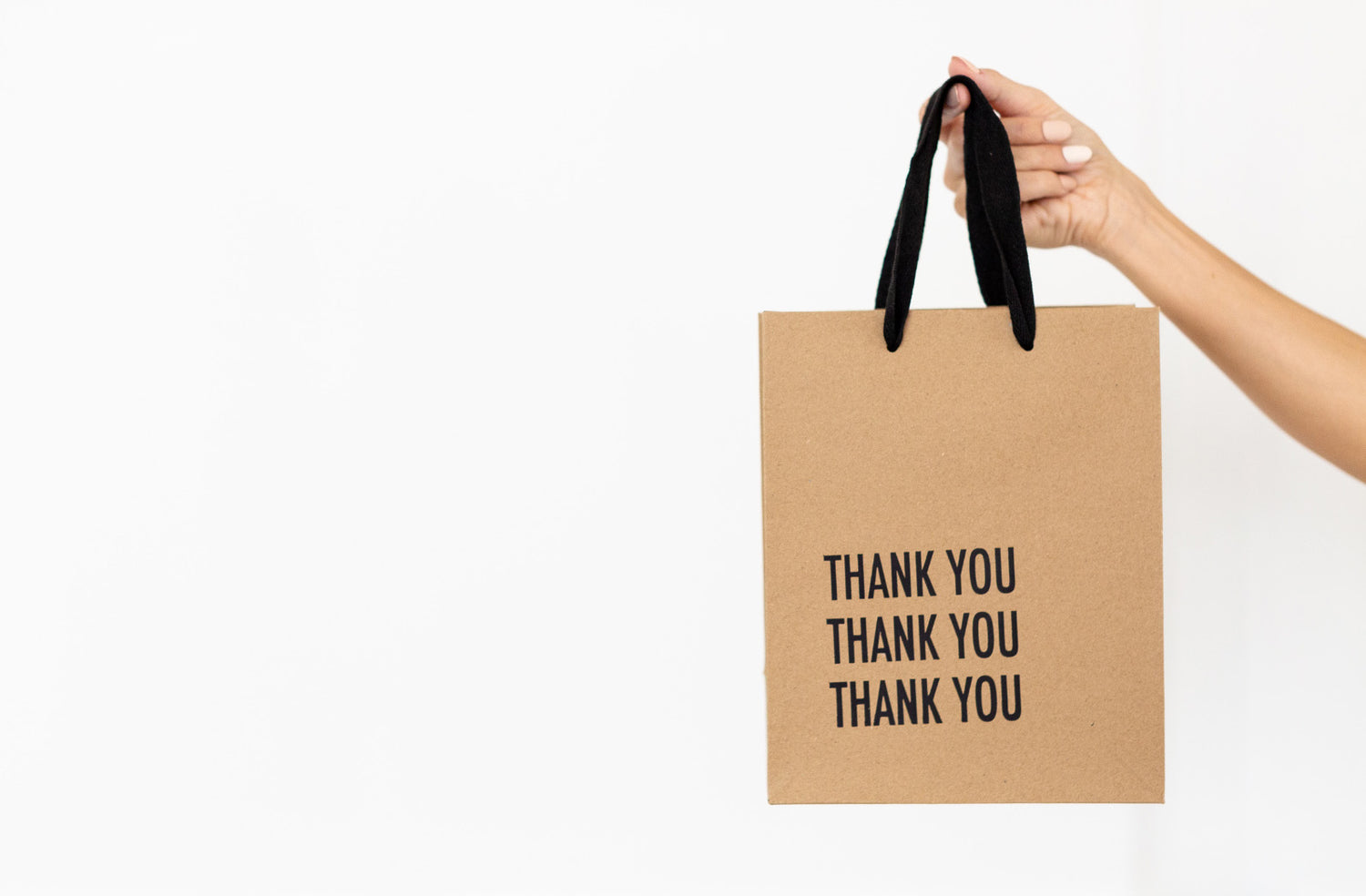 hand holding a shopping bag that says thank you